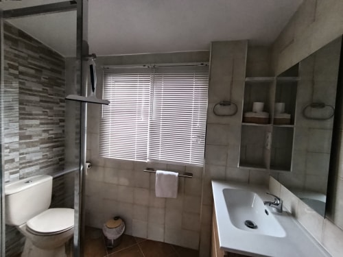 Baño moderno en la villa Las Mellis de Antequera con ducha, lavabo, inodoro y paredes alicatadas