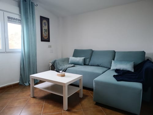 Sala moderna con sofá seccional turquesa, mesa de café blanca y vistas a las montañas en la villa Las Mellis de Antequera