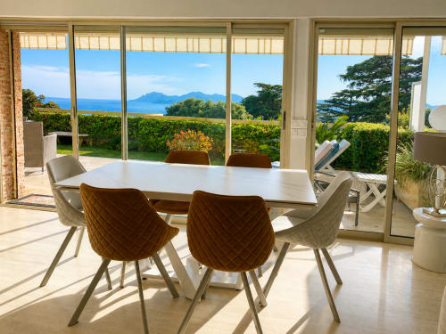 Elegant dining room with sea views at Le Saint Georges apartment in Cannes, featuring modern table and upholstered chairs