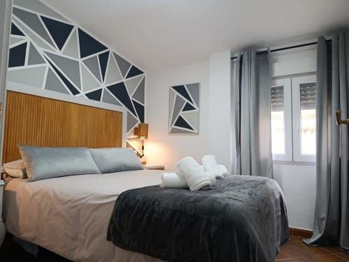 Moderno dormitorio en villa Las Mellis, Antequera, con arte geométrico en pared, cabecero de madera y vistas a las montañas