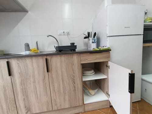 Cocina moderna con muebles de madera, encimera negra, azulejos blancos y electrodomésticos de acero inoxidable en villa Las Mellis