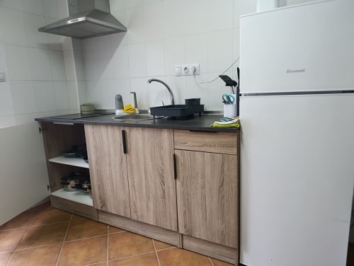 Cocina con gabinetes de madera, encimera negra, estufa y refrigerador en villa Las Mellis, Antequera