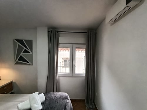 Moderna habitación en villa Las Mellis de Antequera con cama, cortinas grises, puertas al balcón y vistas a la montaña