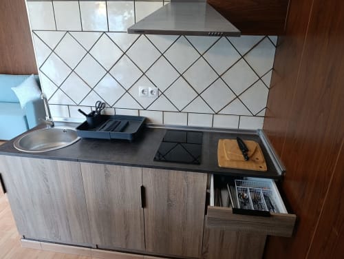 Cocina moderna con encimera negra, azulejos blancos con patrón de diamante, estufa a gas y cabinetería de madera en Luna