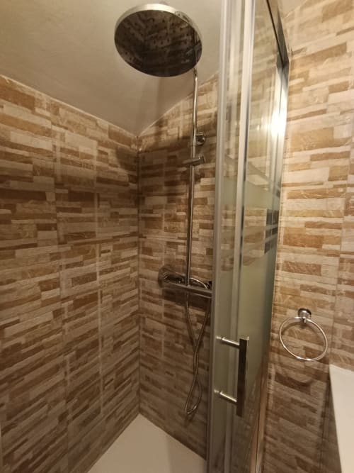 Moderna cabina de ducha con paredes de cerámica tipo madera y ducha tipo lluvia en la villa Las Mellis de Antequera
