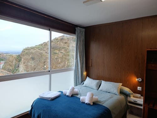 Dormitorio con vistas a la montaña en la villa Las Mellis de Antequera, con cama, revestimiento de madera y paisaje panorámico