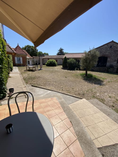 Terrasse ombragée avec vue sur le jardin de la cour du gîte Le Domaine les Olivoux à Pomport, France
