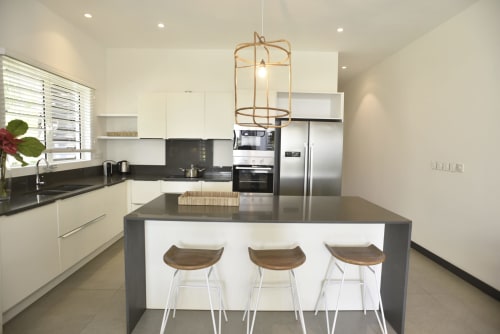Modern kitchen with white cabinetry, dark countertops, stainless steel appliances, central island with bar seating, and