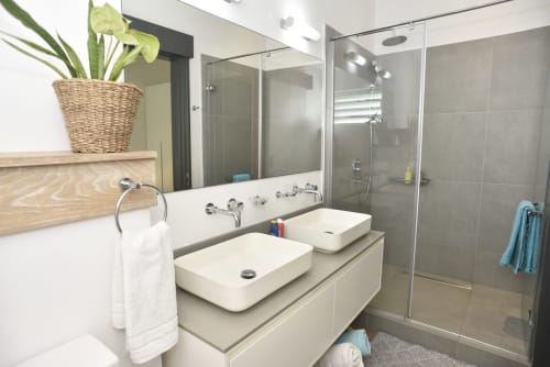Modern bathroom in O'Biches Premium Holiday Apartment with dual sinks, shower enclosure, and plant decor
