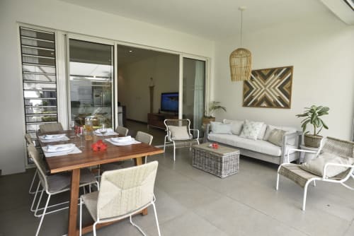 Modern open-plan apartment in Trou-aux-Biches with dining area, lounge seating, and garden views through glass doors