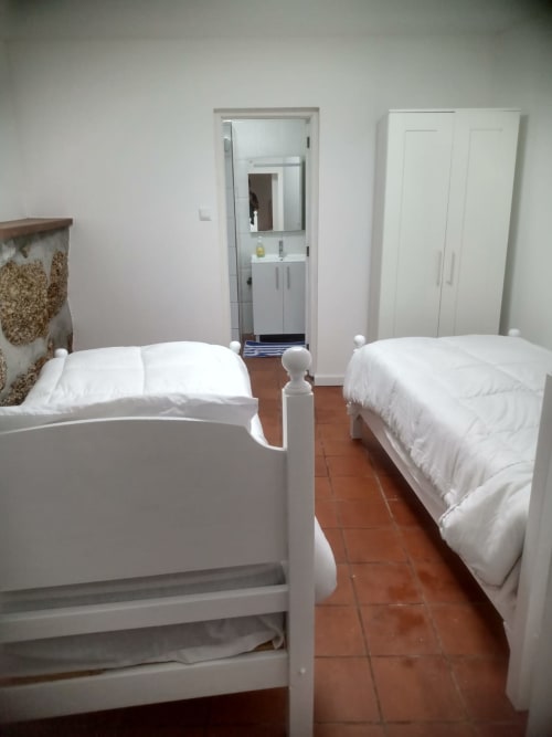 Camas de casal na hospedaria Casa Augusta, quarto C5 Mariquinha em Braga, Portugal com roupas de cama brancas e piso de madeira