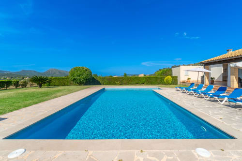 Piscina de lujo en Massa Properties en Artà con tumbonas azules, terraza y vistas a las montañas