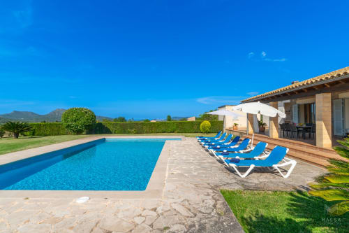 Villa de lujo con piscina en Artà, tumbonas, terraza y vistas a las montañas bajo cielo azul