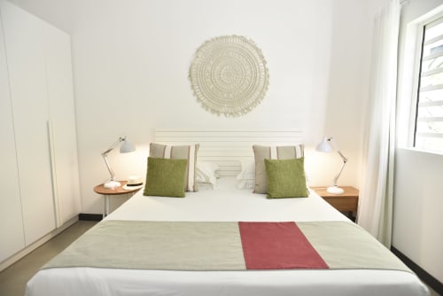 Bright bedroom in O'Biches Premium Holiday Apartment, Trou-aux-Biches with white bedding, green pillows, bedside lamps, and