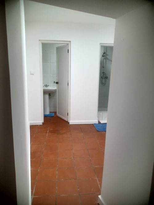 Quarto C5 da pousada Casa Augusta em Braga, Portugal com paredes brancas, piso de azulejo terracota e entrada para banheiro