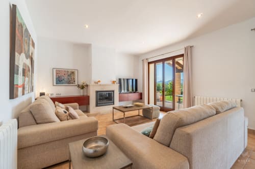 Amplia sala de estar en Massa Properties de Artà con sofás beige, chimenea y vistas al jardín