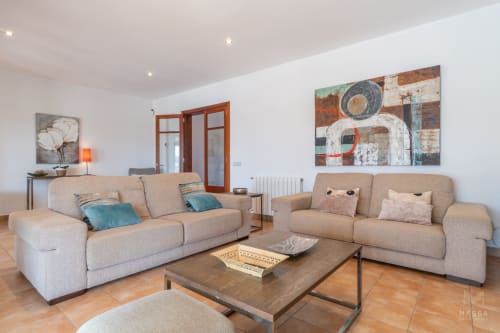 Sala de estar moderna en Massa Properties en Artà con sofás beige, mesa de café de madera y obras de arte contemporáneo