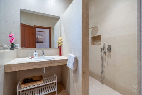 Baño moderno en Massa Properties en Artà con tocador de madera, flores rosas y amplia zona de ducha