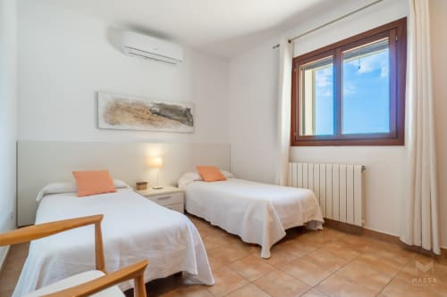Habitación doble con sábanas blancas, detalles naranjas y vistas al mar en Massa Properties, Artà
