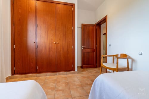 Dormitorio espacioso en Massa Properties de Artà con armario de madera, suelo de terracota y mobiliario moderno