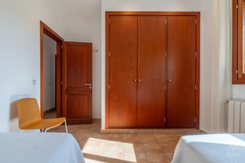 Amplio dormitorio en Massa Properties en Artà con puertas de madera, camas gemelas y mobiliario moderno