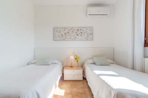 Habitación doble con dos camas blancas, cabecero compartido y luz natural en el hotel Massa Properties de Artà