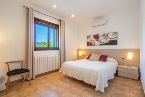 Luminosa habitación con cama queen, suelo de madera y vistas al jardín en el hotel Massa Properties de Artà