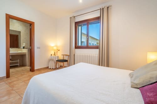 Dormitorio moderno en Massa Properties en Artà con cama blanca, baño ensuite, detalles de madera y vistas a la montaña