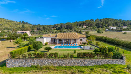 Villa de lujo en Artà con piscina, terraza, jardines cuidados y muro de piedra, rodeada de campos mallorquines