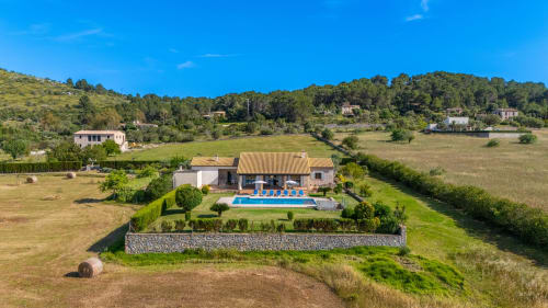 Villa de lujo con piscina en Artà, Mallorca, rodeada de campos verdes y pinos bajo cielo azul