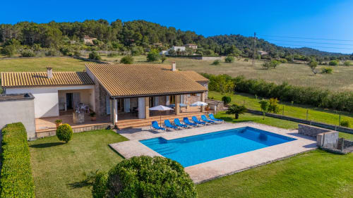 Villa de lujo en Artà con piscina, tumbonas azules y vistas al campo mediterráneo