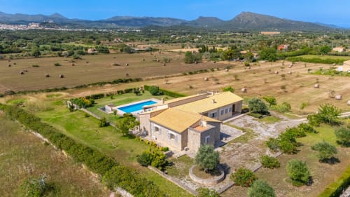 Villa de piedra moderna con piscina en la rural Artà, España, rodeada de campos verdes y montañas