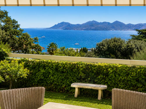 Terrasse de jardin privé à Cannes avec vue mer, chaises longues et îles méditerranéennes à l'horizon
