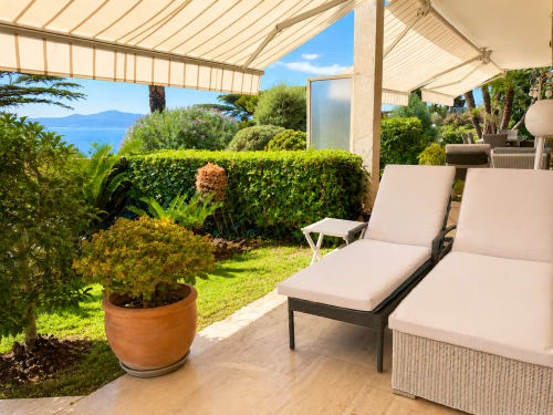 Luxury terrace with loungers under retractable awning, manicured garden, sea view in Cannes Californie apartment