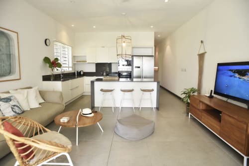 Modern open-plan apartment with white kitchen, island seating, living area, and flat-screen TV at O'Biches Premium Holiday