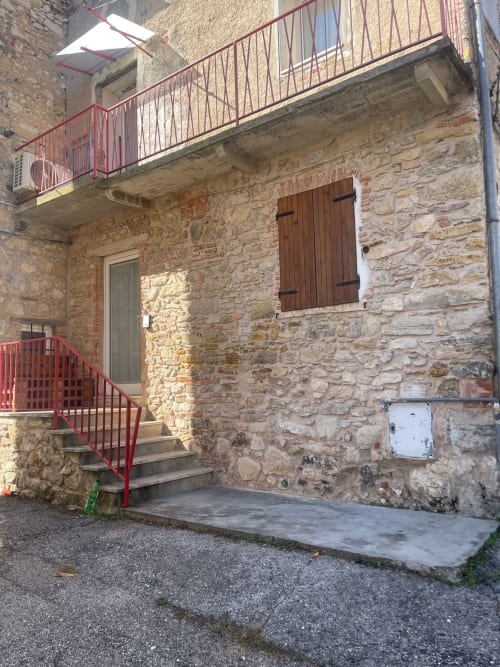 Ingresso dell'appartamento Casa Carmelo a Schio con facciata in pietra, ringhiere metalliche rosse e persiane in legno
