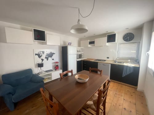 Cucina open-plan moderna con zona living dell'appartamento Casa Poleo a Schio, Italia: tavolo in legno, divano blu e acciaio inox