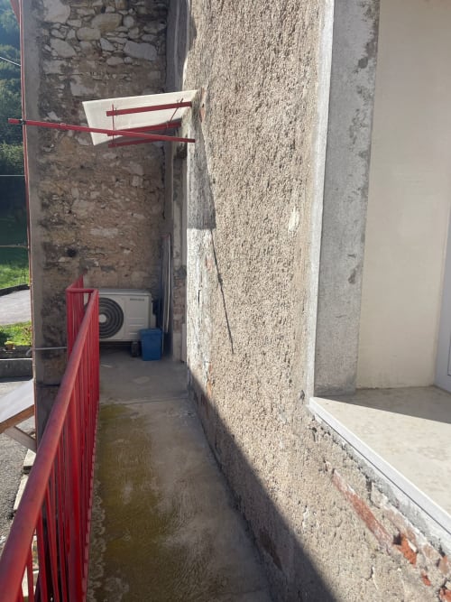 Stretto vicolo esterno di Casa Carmelo Schio con ringhiera rossa e unità HVAC nella zona residenziale