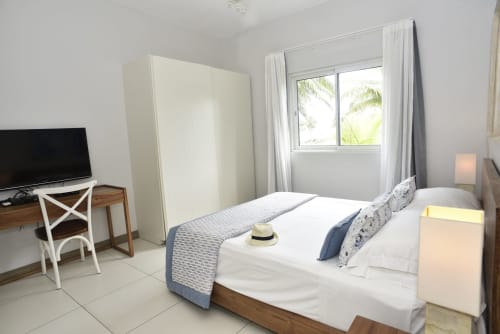 Bright beachfront apartment bedroom with queen bed, TV, desk, and sea views at Unik Properties, Pointe d'Esny, Mauritius
