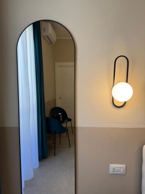 Corridoio moderno dell'hotel con specchio ad arco e applique murale contemporanea presso la Maison ì Room di Reggio Calabria