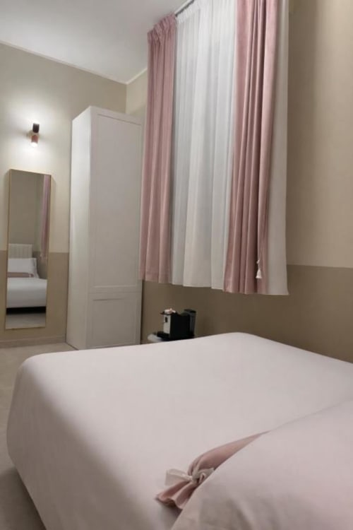 Camera da letto moderna al Maison ì Room di Reggio Calabria con letto bianco, tende a righe rosa, armadio e giardino