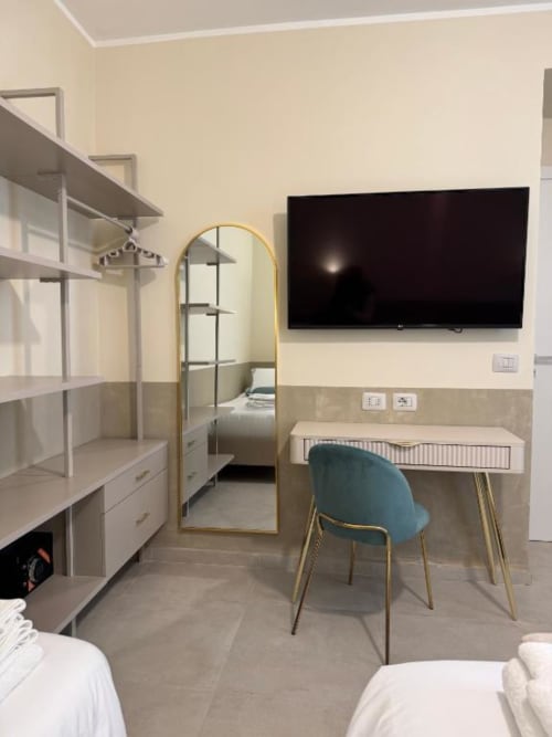 Appartamento deluxe presso Maison ì a Reggio Calabria con scrivania, TV, specchio cornicato oro, sedia blu e arredi moderni