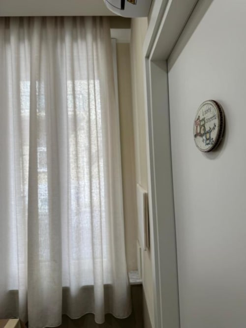 Luminoso angolo di lussuoso appartamento presso Maison ì Room a Reggio Calabria con tende trasparenti, pareti bianche e orologio decorativo