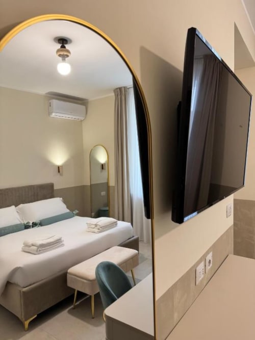 Camera da letto Deluxe moderna in Maison ì Room a Reggio Calabria con TV a schermo piatto, specchio decorativo e biancheria bianca