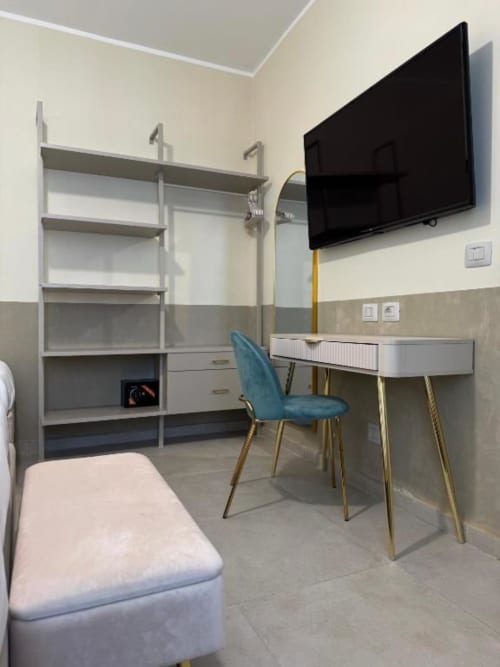 Moderno appartamento di lusso a Reggio Calabria con scrivania, sedia blu, TV a parete, libreria e design contemporaneo