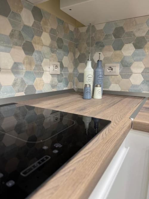 Cucina moderna con rivestimento in piastrelle esagonali, piano di lavoro in legno, piano cottura a induzione e flaconi nella Maison ì Room