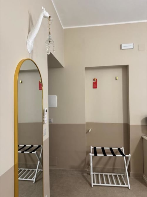 Moderno corridoio dell'hotel con specchio cornice dorata, scaffali bianchi e cartelli porta rossi presso Maison ì Room a Reggio Calabria