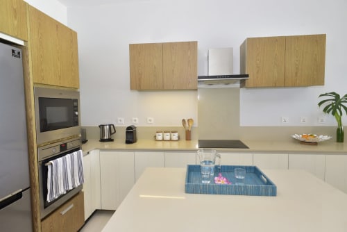 Modern kitchen with cream cabinetry, oak wood upper cabinets, stainless steel appliances, and dining area at Pointe d'Esny