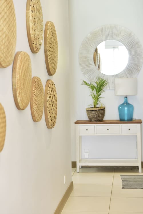 Modern entryway with woven wall baskets, framed mirror, blue glass lamp, potted plant, and white console table at Pointe