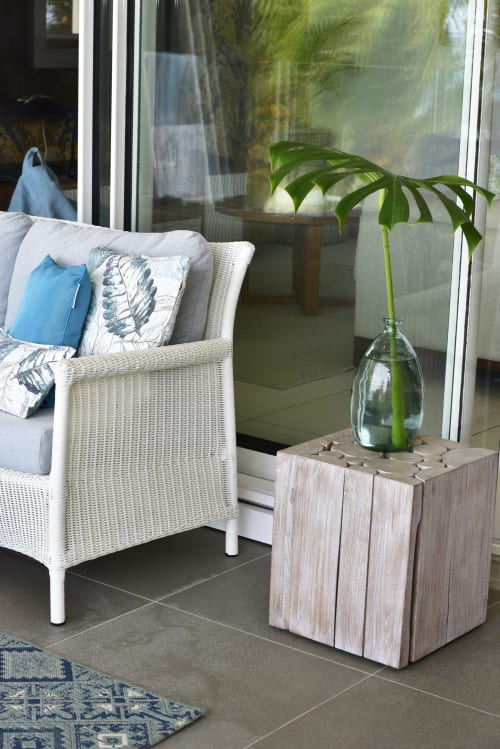 Luxury beachfront apartment balcony with wicker chair, blue pillows, and fresh green plant in glass vase at Pointe d'Esny,